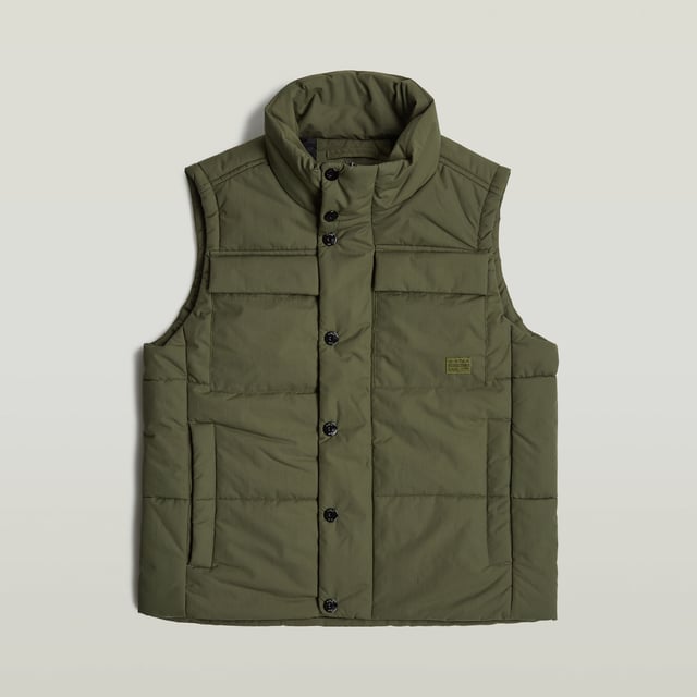 Raised collar. Sleeveless. Straight hem. Flap pockets at the chest, side pockets- hidden snap button closure. Inner pocket and hanger loop. Concealed zipper closure, snap buttons. Zip & snap closure. Densely woven fabric, enriched with a PFC free water repellent finish. Vest Foundation is padded and stitched through horizontally. Pockets are created at the chest as well as the sides. The zipper closure is covered by a wind blocker with snap buttons. Inside, an additional pocket is created to complete this sleeveless padded jacket. Densely woven. Compact woven. Coated with a high performance water repellent finish for optimal functionality.