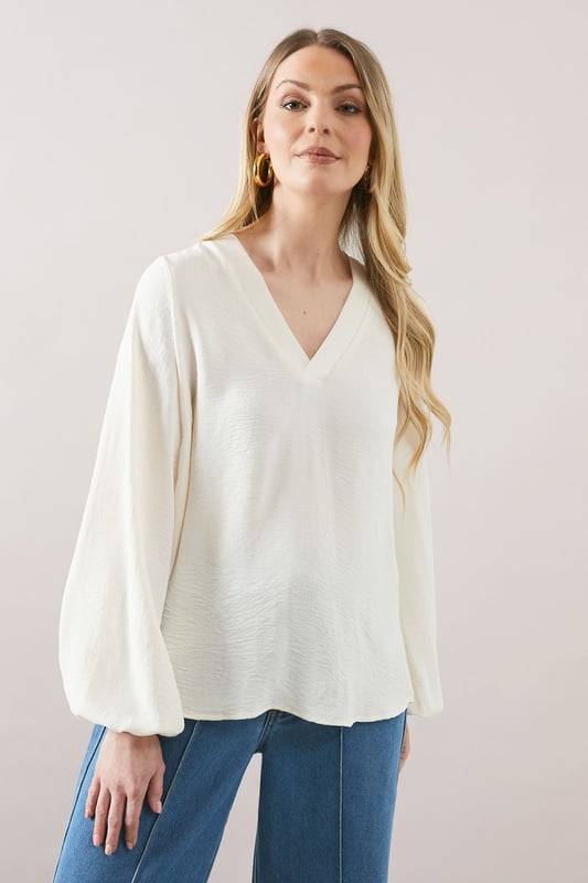 Elegant V-neckline for a flattering silhouette
        Voluminous balloon sleeves add a touch of drama
        Relaxed, over-the-head design for effortless wear
        Versatile woven fabric suitable for various occasions
        Subtle textured finish for added visual interest
    
    Embrace sophisticated comfort with this Wallis over-the-head top. The flowing silhouette and statement balloon sleeves create a look that's both relaxed and refined. Perfect for daytime engagements, this versatile piece can be styled for a range of casual events. Pair it with wide-leg trousers and sandals for a chic family lunch, or team it with your favourite jeans and trainers for a stylish weekend brunch. The V-neckline offers a feminine touch, while the textured fabric adds depth to your ensemble. For a polished daytime look, accessorise with delicate gold jewellery and a woven handbag. This top effortlessly bridges the gap between comfort and style, making it an essential addition to your wardrobe for those occasions when you want to feel put-together yet at ease.