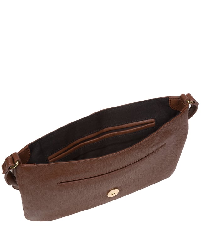 This stylish, sleek and spacious cross body bag from Pure Luxuries London's Marylebone Collection is a gem of a bag. The 'Ruby' features a fold-over top secured with a magnetic press-stud opens to reveal a 100% cotton lined interior and features three slip pockets concealed - ideal for all your essentials. The accessory is adorned with a slim and adjustable leather strap with a drop leather of 65cm. The design is finished with attractive gold-coloured metal fittings and zips which are a luxurious addition alongside the blind embossed Pure Luxuries logo which is a sophisticated finishing touch