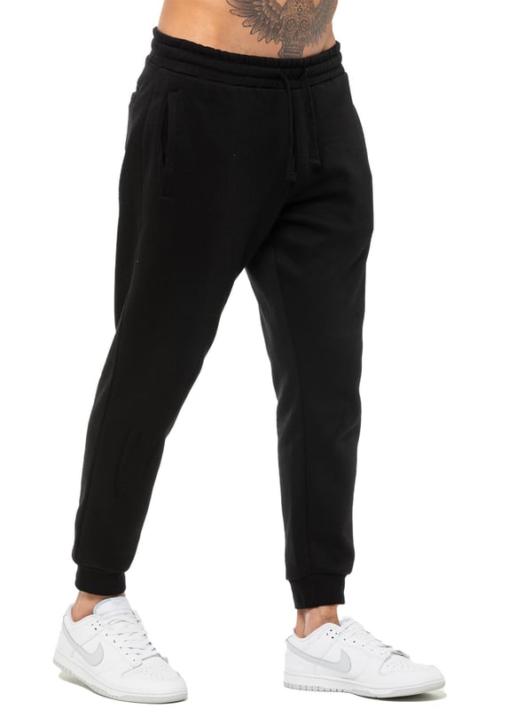 Enzo Mens Regular Fit Joggers. Elasticated Waistband With Adjustable Drawstring. Features 2 Side Slash Pockets & Single Welt Back Pocket. Cuffed Ankle. Features EZ Logo.