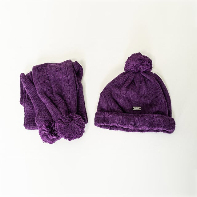 Knitted hat and scarf set.
 Tricot knit hat.
 Metal insert with the brand name.
 Hair tassel on top.
 Scarf.
 Two synthetic fur tassels on the sides.
 Size equivalence:
 30 cm -- 0/1 MONTH
 35 cm -- 3 MONTHS
 42 cm -- 1/3 MONTHS
 46 cm -- 6/9 MONTHS
 48 cm -- 12/18 MONTHS
 50 cm -- 24/36 MONTHS
 53 cm -- 4/5 YEARS
 56 cm -- 6/8 YEARS
 Measures: Length 101 cm - Width 10cm
 Composition: 75% Cotton, 20% Polyamide, 5% Wool
 Care:
- Wash maximum at 30ºC.
 - Iron at medium temperature, max. 110ºC.
 - It is not allowed to use a dryer.
 - Do not use bleach.
 - Does not support dry cleaning.