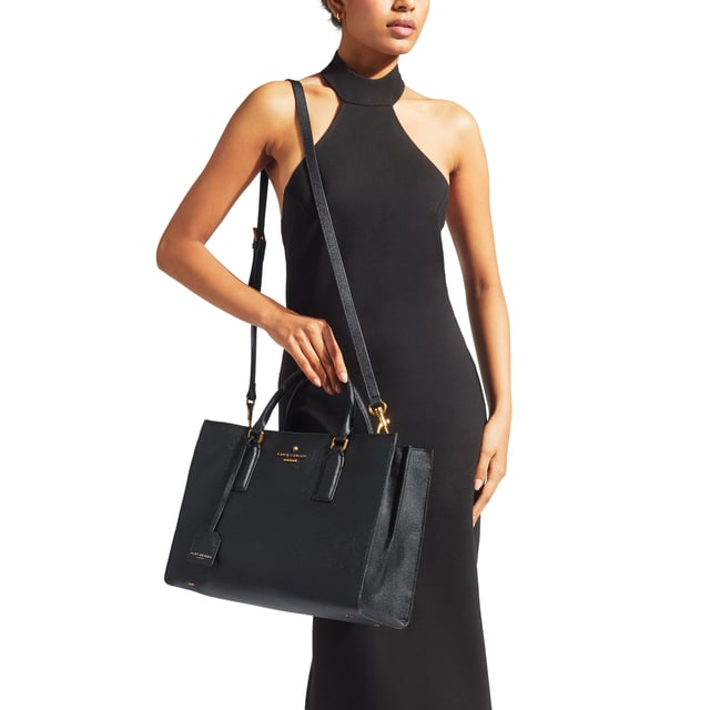 This Kurt Geiger Highgate Tote is crafted from a black Saffiano leather meaning it can withstand scratches and is suitable for regular outdoor use.The front of the bag features antiqued brass branding with micro eagle head emblem. Dimensions: 25cm (H), 34cm (L), 15 cm (D). Strap length: 124cm.