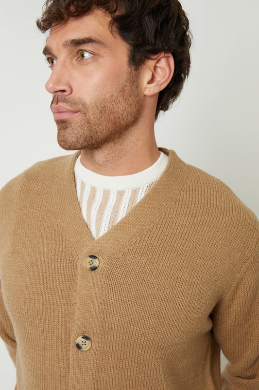 Be comfortable in style in this button down, knitted cardigan from Threadbare. With a V-neckline, ribbed cuffs and hem, this button up cardigan is the perfect addition to your wardrobe. Complete with branded metal tab above the hem, five mock horn buttons and two patch pockets. Made from a super-soft yarn with wool, this style is ideal for layering. Pair with dark denim jeans, a white t-shirt and boots for a stylish, casual look.