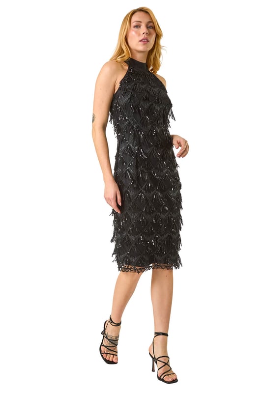 Tassle Trapeze Dress from Roman. Add a touch of glamour to your wardrobe with our halter neck trapeze dress. Showcasing a feminine halter neckline and sleeveless style, this dress boasts an elegant bodycon shape adorned with embellished details and a stunning tassel design. Crafted from a comfortable woven fabric, this dress is perfect for all-day wear. Finish this look above knee length with heels and a bolero for a special occasion!