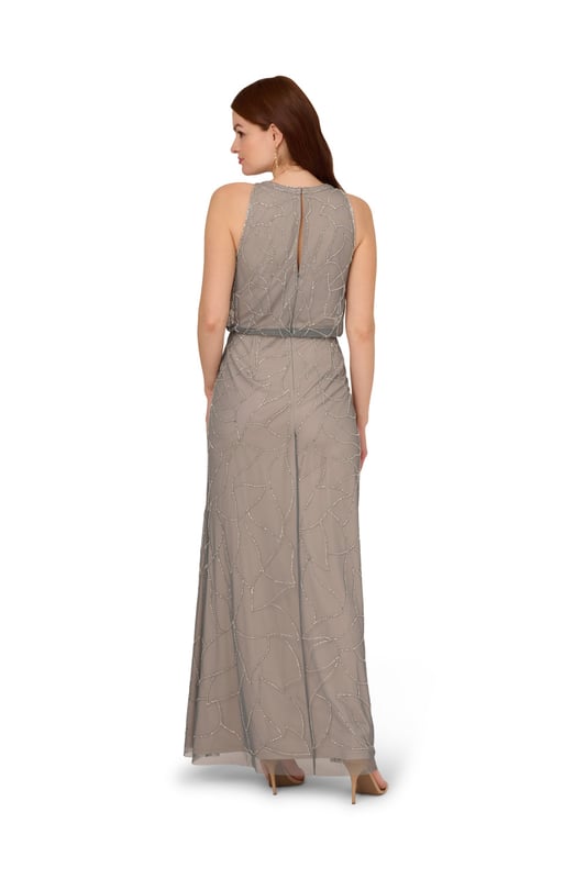 Timelessly sparkle at your next formal event in this blouson gown. This formal dress features a sleeveless blouson bodice, a halter neckline, and a mermaid skirt. Fully lined, this evening gown is designed with mesh knit fabric that is fully embellished with sequin and beaded floral deco patterns. A hidden zipper closure at the centre back completes this sleeveless gown. Paired with nude heels and simple accessories, this beaded dress is ideal for black-tie events or bridal parties.