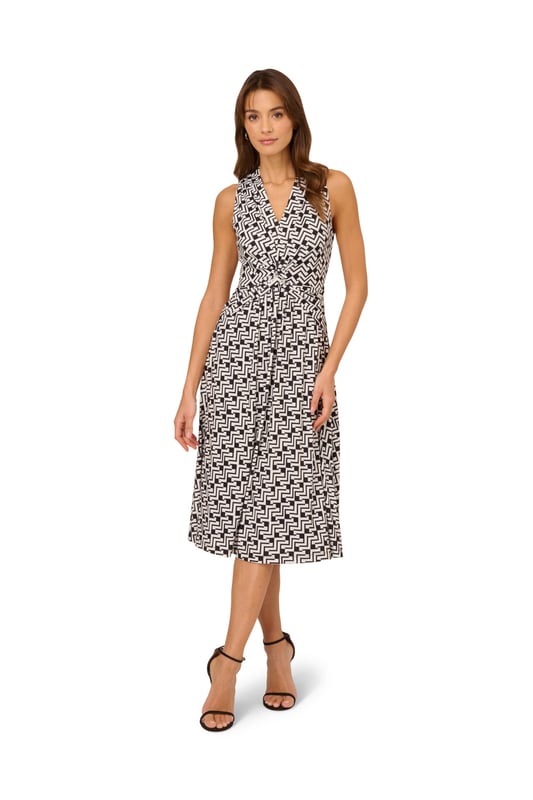 Great for work and for play, this sleeveless dress is a timeless look. This midi dress features a fitted bodice with a v-neckline, a knotted detail at the centre of the waist, and a soft skirt. Crafted from jersey fabric with comfortable stretch, this pull-on day dress boasts a geometric print. Styled with a blazer at the office, this sleeveless dress will take you all the way through happy hour.