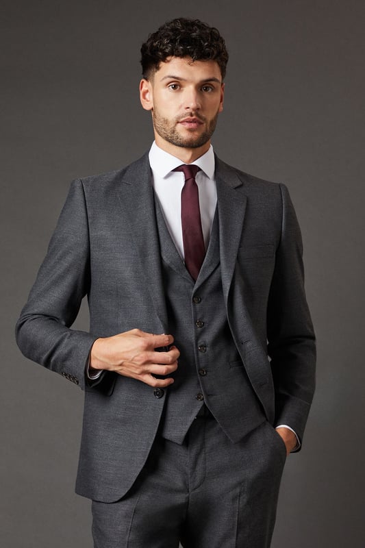 Slim fit design for a modern, tailored silhouette
        Tweed-look fabric adds texture and sophistication
        Notched lapels and two-button closure for classic styling
        Flap pockets and chest welt pocket for practicality and style
        Versatile charcoal hue suitable for various occasions
    
    This Burton slim fit suit jacket presents a refined option for the discerning gentleman. The tweed-look fabric lends a touch of traditional charm to a contemporary silhouette, making it an ideal choice for the modern man who appreciates classic style. Perfect for smart casual events or more formal occasions, this jacket can be styled with matching trousers and a waistcoat for a complete suited look. For a sophisticated ensemble, pair with a crisp white shirt and a deep burgundy tie as shown. Alternatively, dress it down with a light blue Oxford shirt and dark denim for a smart pub outing with mates. The versatile charcoal hue ensures this jacket will become a staple in your wardrobe, easily transitioning from office to evening wear. Whether you're heading to a business meeting or a weekend wedding, this Burton suit jacket will have you looking sharp and feeling confident.