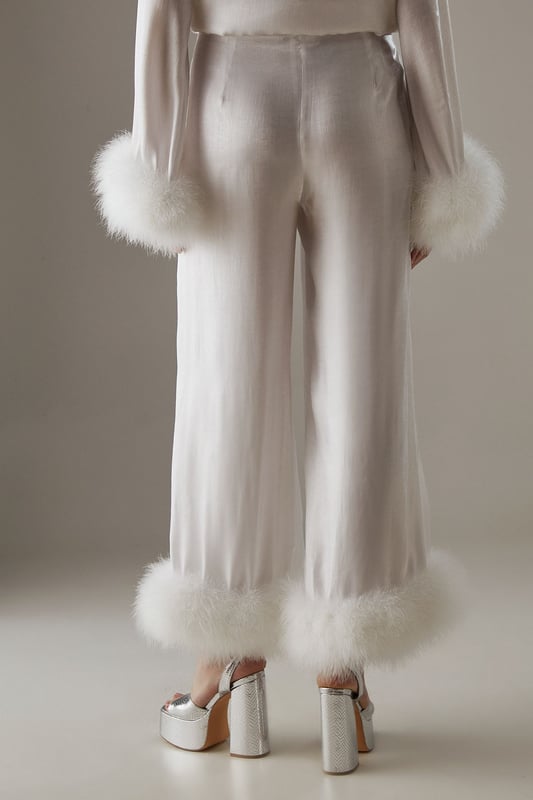 Luxurious feather trim adorning cuffs and hem
        Wide-leg silhouette for a dramatic, flowing effect
        High-waisted design for a flattering fit
        Iridescent fabric adding a subtle shimmer
        Ankle-length cut perfect for showcasing statement footwear
    
    Make a grand entrance at your next formal event with these show-stopping wide-leg trousers from Warehouse. The iridescent fabric catches the light beautifully, whilst the opulent feather trim at the cuffs and hem adds a touch of old Hollywood glamour. Style these trousers with a sleek, fitted top to balance the voluminous silhouette. For an ultra-chic ensemble, pair with metallic platform sandals and a clutch bag. These trousers are versatile enough for a range of occasions, from black-tie galas to winter weddings. The high-waisted cut elongates the legs, creating a statuesque silhouette that's sure to turn heads. Embrace your inner fashionista and let these trousers be the star of your outfit.