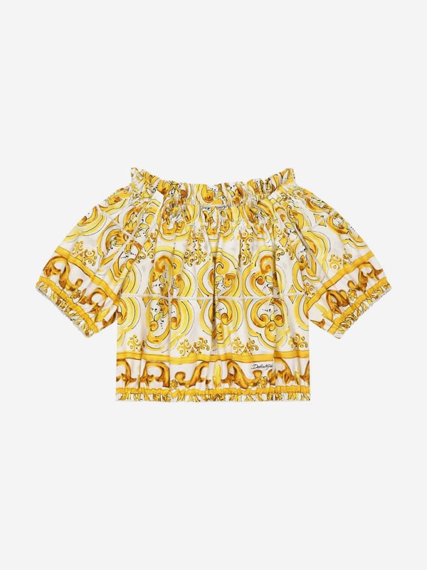 Dolce & Gabbana utilise new technological properties to create captivating aesthetics. This girls blouse is a part of the FW24/25 Girl‚  Collection. Depicted in Majolica, a symbol of Italian craftsmanship, it comes in lemon yellow, brightened up by pure white, taking inspiration from Sicilian pottery. Envisioned in cotton poplin with all-over yellow majolica print via a cropped fit and short puff sleeves, showcasing elasticated cuffs.  Made in Italy Boat Neck With Dropped Shoulders Stretch Hem Placed Print Due to "Handmade" Aspect 100% Cotton