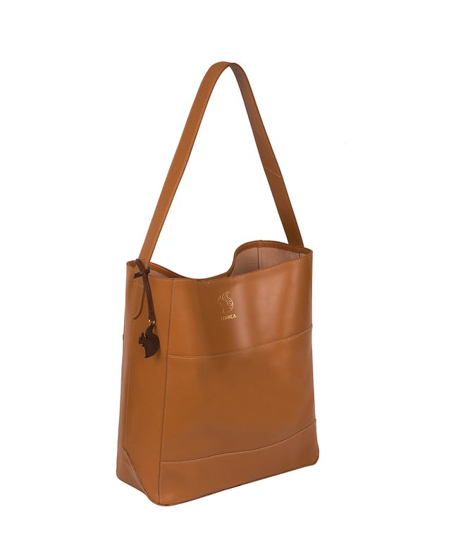 The 'Reynolds' shoulder bag from Conkca London's Camden Collection is that it is handcrafted from high-quality vegetable-tanned gold standard leather for a smooth and sophisticated finish. A magnetic clasp secures an open top and comes with an unlined, soft to the touch natural leather interior. Features a fuss-free, spacious central compartment for convenient storage. Fitted with a leather strap and is adorned with the inimitable Conkca squirrel charm and logo.