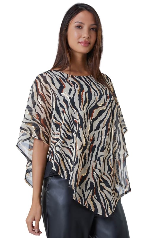 Animal Foil Overlay Stretch Top from Roman. Take a walk on the wild side with this luxurious zebra print party top. Designed with an asymmetrical chiffon overlay that features shimmering foil print, this style is sure to turn heads at your next special occasion. This pull on style has a soft stretch jersey lining for maximum comfort as well as a classic round neckline and short sleeves. Wear with faux leather trousers and heeled boots for style that screams Winter glamour.