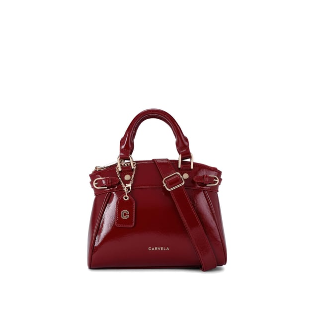 This Carvela Mini Valentina Tote bag features a wine red exterior in a trapeze style. There are two buckled straps across each side of the bag and branded gold tone hardware across the bag. Dimensions: 19cm (H), 22cm (L), 10cm (D). Strap length: 111cm.