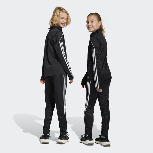 Essential training gear from adidas. Before you hit the pitch for that chilly winter session, layer up in these juniors' Tiro 23 Club football pants. Their slim, streamlined fit and moisture-absorbing AEROREADY will keep you flying through sprints and rondos. Once you reach perfect temperature, ankle zips make pulling them off over your boots a breeze.Made with 100% recycled materials, this product represents just one of adidas' solutions to help end plastic waste.  - Slim fit - Mid-rise elastic waist with drawcord - 100% polyester (recycled) - AEROREADY - Front zip pockets - Ankle zips  Shipped by adidas