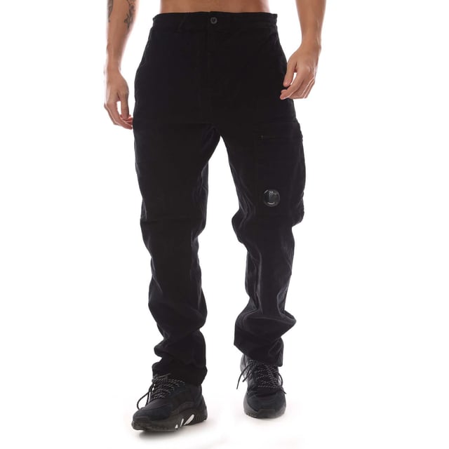 Mens C.P. Company Corduroy Lens Pants in black.- Adjustable drawstring at inner waistband.- Zip fly and button fastening.- Side welt pockets.- Rear patch pocket.- Cargo zip pocket with Lens detail.- Old dyed.- Regular fit.- 97% Cotton  3% Elastane.  Machine washable.- Ref: 17CMPA123A 006410O 999