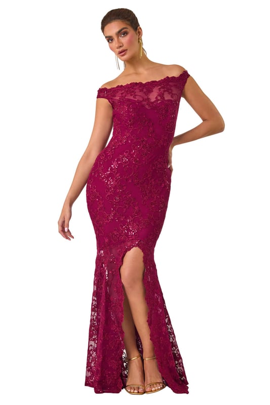 Lace Scallop Edge Front Split Maxi Dress from Roman. Get ready to make a statement in our stunning lace maxi dress. The feminine bardot neckline is adorned with delicate scalloped lace details, adding a touch of elegance to the look. Crafted from a stretch woven fabric, this bodycon dress hugs your shape beautifully and finishes at a flattering maxi length with a mermaid edge and front split for added drama. Pair with heels and a bolero for an unforgettable look!