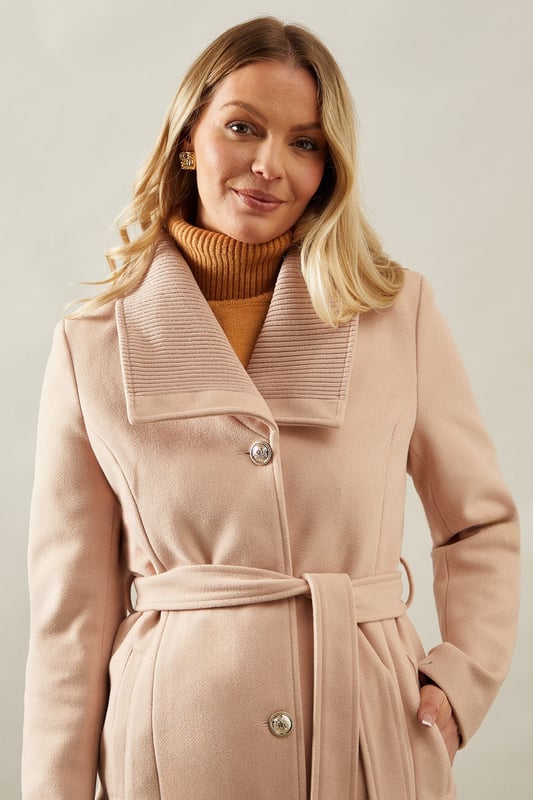 Elegant knitted collar for added sophistication
        Wrap design with button-through closure for versatile styling
        Long length offers maximum coverage and warmth
        Belted waist creates a flattering silhouette
        Functional side pockets for practicality
    
    This Wallis Knitted Collar Button Through Wrap Coat is the epitome of refined elegance. Perfect for the woman who appreciates sophistication without compromising on comfort, this coat is a versatile addition to any wardrobe. The wrap design allows for customisable fit, while the button-through closure adds a touch of classic charm. Style it over a sleek midi dress and pair with heeled boots for a polished look at formal events. For smart casual occasions, layer it over tailored trousers and a fine knit jumper, completing the ensemble with leather ankle boots. The long length and belted waist not only provide warmth but also create a striking silhouette that's sure to turn heads. Whether you're attending a business meeting or heading to a sophisticated dinner, this coat will ensure you look impeccably put-together while feeling effortlessly comfortable.
