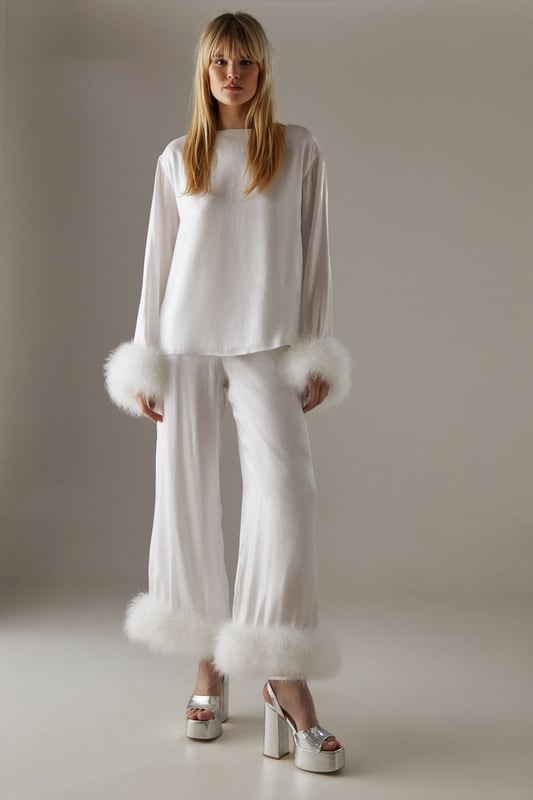 Luxurious feather trim adorning cuffs and hem
        Wide-leg silhouette for a dramatic, flowing effect
        High-waisted design for a flattering fit
        Iridescent fabric adding a subtle shimmer
        Ankle-length cut perfect for showcasing statement footwear
    
    Make a grand entrance at your next formal event with these show-stopping wide-leg trousers from Warehouse. The iridescent fabric catches the light beautifully, whilst the opulent feather trim at the cuffs and hem adds a touch of old Hollywood glamour. Style these trousers with a sleek, fitted top to balance the voluminous silhouette. For an ultra-chic ensemble, pair with metallic platform sandals and a clutch bag. These trousers are versatile enough for a range of occasions, from black-tie galas to winter weddings. The high-waisted cut elongates the legs, creating a statuesque silhouette that's sure to turn heads. Embrace your inner fashionista and let these trousers be the star of your outfit.