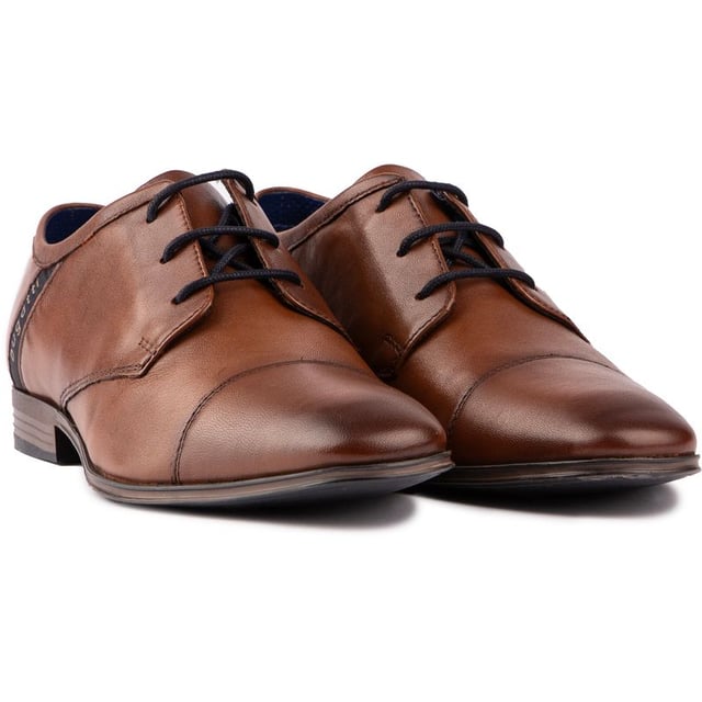 Con un estilo elegante y un diseño elegante. El zapato derby con cordones Bugatti Gibson Toe Cap color canela es imprescindible para el caballero moderno. Con una lujosa parte superior de cuero con el logotipo característico del diseñador. un refuerzo elástico para mayor comodidad y ajuste. Cordones encerados y plantilla acolchada. Estos zapatos son inteligentes sin esfuerzo. Una excelente opción para complementar tu ropa de oficina. traje de negocios o armario de noche.
