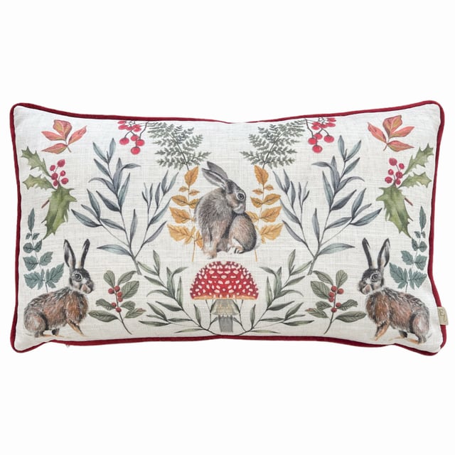 An adorable cushion featuring three posing winter hares among winter foliage and a toadstool, set on a fresh white background. The hand painted watercolour design is printed on polylinen fabric, with a plush plain red velvet reverse, contrasting piped trim and zip fastening. Ideal for bringing a touch of nature to your home.