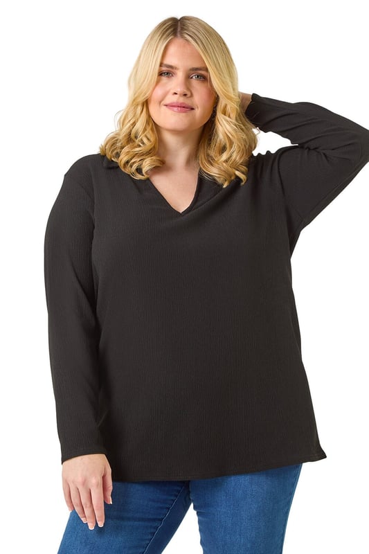 Curve Stretch V-Neck Collared Top from Roman. Elevate your casual style with this V-Neck jersey top, perfect for the Autumn/Winter season. Crafted from a textured jersey fabric, this top features a classic V-Neckline with a collar detail and comfortable long sleeves. The below hip length offers a flattering silhouette that pairs effortlessly with the matching trousers for a coordinated look. Complete your outfit with boots and a jacket for a chic and cozy ensemble.