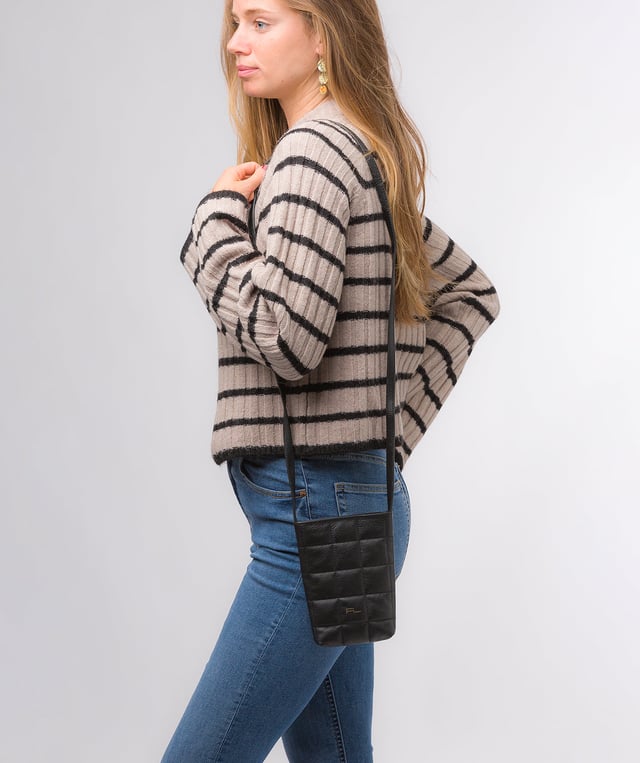 The 'Elouise' cross body phone bag from the Pure Luxuries Marylebone collection is handcrafted from high-quality, genuine Nappa leather with a natural super-soft touch. The eye-catching quilted design on the front gives the bag a unique silhouette, along with extra protection. A concealed magnetic closure keeps the contents of the bag secure. The interior is lined with 100% cotton and includes a slip pocket and two card slots. Comes with a matching and adjustable slim leather strap with a maximum drop length of 65cm. The minimalist Pure Luxuries logo is embossed in gold foil for a beautifully simple finishing touch.