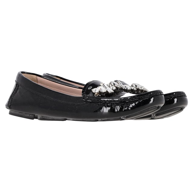 VINTAGE, NP WIE NEU  
Tauchen Sie ein in die Raffinesse mit den Crystal Detail Loafers von Miu Miu aus schwarzem Lackleder. Diese auffälligen Slipper zeichnen sich durch ein elegantes schwarzes Lacklederfinish aus, das mit funkelnden Kristallelementen verziert ist, die einen Hauch von glamourösem Flair verleihen. Das zeitlose Design der Slipper wird durch diese markanten Details aufgewertet, wodurch sie sowohl für berufliche Umgebungen als auch für Abendveranstaltungen perfekt geeignet sind. Erleben Sie die perfekte Mischung aus Eleganz und Glanz mit jedem Schritt, den Sie machen.  

Miu Miu Crystal Detail Loafers aus schwarzem Lackleder  

Zustand: Sehr gut  
Abnutzungserscheinungen: Sehr leichte Markierungen an Sohlen und Innensohlen.  
Verpackung: Keine  
Farbe: Schwarz  
Material: Leder | Lackleder  
Größe: EU37/UK4/US7  
Maße:  
SKU: TONPUGBSH377100W