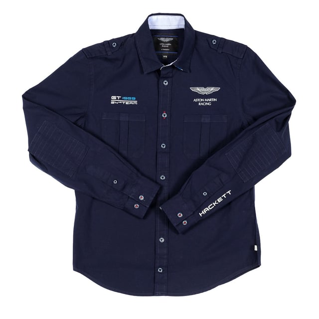 Jongenshemd met lange mouwen van Aston Martin Racing.
 Kraag met kapel.
 Knoopsluiting aan de voorkant.
 Twee open zakken op de voorkant.
 Eigen bedrukking van het merk op de voorkant.
 Gedrukte merknaam op een van de mouwen.
 Manchetten met knoopsluiting.
 Toepassing als elleboogstukken.
 Stoffen label met de vlag van het Verenigd Koninkrijk en de naam van het merk op de onderkant.
 Stoffen label met de merknaam op de achterkant van de hals.
 Naden in toon zichtbaar.
 Samenstelling: 100% katoen
 Onderhoud:
- Maximaal wassen op 30ºC.
 - Strijken op gemiddelde temperatuur, max. 110ºC.
 - Droger is niet toegestaan.
 - Geen bleekmiddel gebruiken.
 - Kan niet chemisch gereinigd worden.