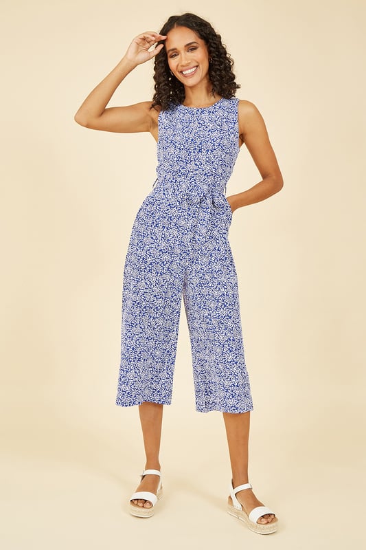 This summer is all about cute prints and this Mela Blue Ditsy Printed Jumpsuit delivers on all counts. Featuring a dainty white floral ditsy print, this piece is designed to flatter all shapes and sizes. Check the waist accentuating self tie belt and elegant, wide legged culotte. Match with a cropped denim jacket and chunky white trainers to complete the look.