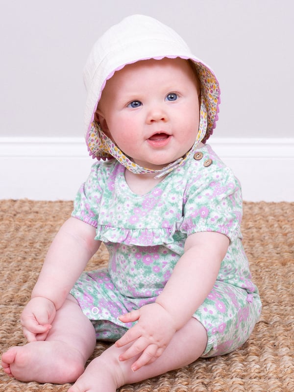 95% organic cotton 5% elastane | Proud to be certified to the Global Organic Textile Standard (GOTS) | Flower patch all-over print | Slub jersey with a little stretch (170-180 gsm) | Coconut button shoulder opening | Popper crotch opening | Short sleeved | Short legs | Frill detail at yoke | Made in Turkey | Machine washable at 40 degrees, or at 30 degrees to be kinder to the planet