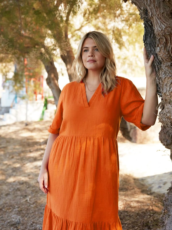 In a beautiful burnt orange, this dress is cut from a textured cotton thats so comfortable to wear. With a nehru collar and lengthening V-neck, it has a tiered design thats flattering and easy to wear. Short sleeves and side seam pockets add extra detail, making it the perfect throw-on summer dress.