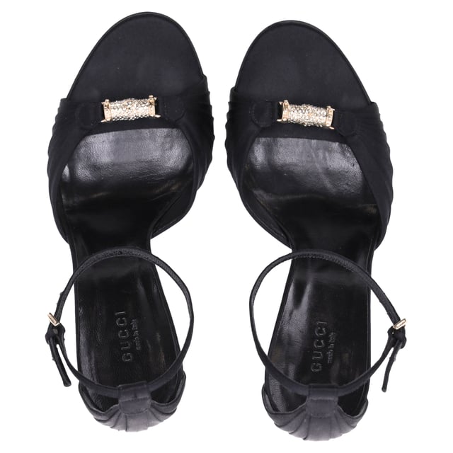 VINTAGE, RRP AS NEW
Elevate your evening ensemble with the Gucci Crystal-Embellished Open-Toe Sandal Heels in luxurious black satin. These stunning heels feature a captivating crystal embellishment that adds a touch of sparkle and glamour, perfect for any special occasion. The open-toe design elegantly showcases your pedicure, while the delicate straps provide a secure fit and enhance the overall allure of the shoe. Crafted from high-quality satin, these sandals not only look fabulous but also offer comfort for all-night wear. Pair them with your favorite cocktail dress or tailored jumpsuit to create a head-turning look that embodies the sophistication of Gucci.

 Gucci Crystal-Embellished Open-Toe Sandal Heels in Black Satin

Condition: Very good
Signs of wear: Minor markings, Lightly used but very well maintained. Minor mark at soles & creasing, light scuffing at the soles and heels.
Packaging: None
Color: Black
Material: Satin | satin
Size: IT38.5/FR39.5/UK5.5/US8.5
Measurements: Heel height: 11; Insole length: 25,5
SKU: NAPPUITSH397907W