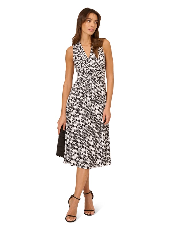 Great for work and for play, this sleeveless dress is a timeless look. This midi dress features a fitted bodice with a v-neckline, a knotted detail at the centre of the waist, and a soft skirt. Crafted from jersey fabric with comfortable stretch, this pull-on day dress boasts a geometric print. Styled with a blazer at the office, this sleeveless dress will take you all the way through happy hour.