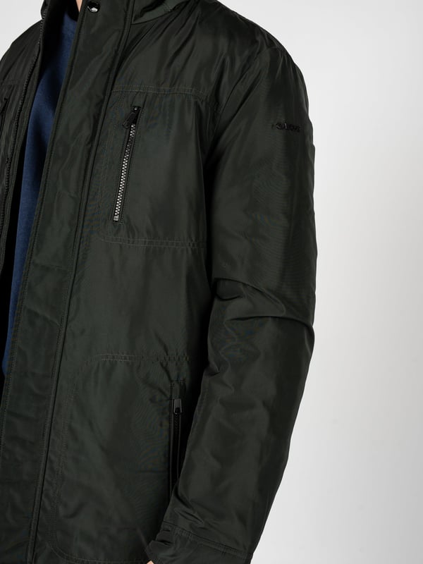 El estilo sencillo es la combinación perfecta de clásico y moderno, lo que hace que esta chaqueta se adapte perfectamente a diversos estilos, desde casual hasta más elegantes, manteniendo su carácter único y minimalista.

En el cuello alto, que añade elegancia a la chaqueta y proporciona protección adicional contra el viento, puedes confiar en los días más fríos, y su diseño sutil hace que la chaqueta gane en universalidad y sea ideal para cualquier ocasión.

Con una capucha oculta en el cuello, este elemento práctico permite una rápida adaptación a los cambios del tiempo, ofreciendo protección contra la lluvia cuando más lo necesitas, sin renunciar a la estética.

Cerrada con una cremallera logotipada y botones a presión, la chaqueta no solo proporciona un cierre seguro y cómodo, sino que también constituye un acento elegante, que subraya sutilmente su carácter de marca.

En el frente, cuatro bolsillos con cremallera ofrecen no solo mucho espacio para los elementos esenciales, sino también garantizan la seguridad de los objetos almacenados, permitiéndote disfrutar de plena funcionalidad y comodidad diaria.

Ajustable con cordones en la cintura, la chaqueta permite un ajuste perfecto al cuerpo, lo que no solo resalta su aspecto moderno, sino que también proporciona confort adicional, adaptándose a tus necesidades individuales.

En la manga izquierda, un detalle de la marca constituye una referencia sutil, pero clara, a la marca, añadiendo prestigio a la chaqueta y destacando su exclusividad, lo que seguramente atraerá la atención de aquellos que valoran los detalles de marca.

Hecha de un tejido de alta calidad, transpirable y resistente al agua, la chaqueta no solo proporciona comodidad térmica y protección contra la humedad, sino que también cuida la adecuada circulación del aire, lo que la hace una opción ideal para diversas condiciones climáticas.