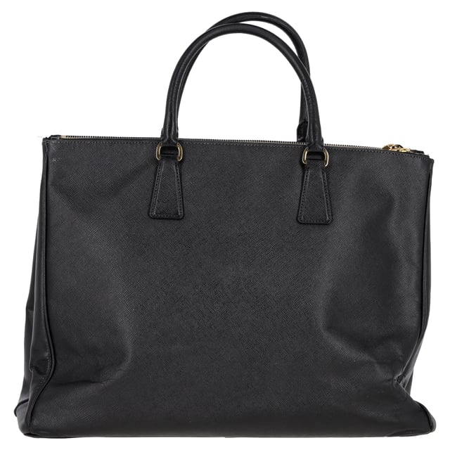 VINTAGE, NEUPREIS WIE NEU  
Die Prada Double Zip Executive Tote Bag aus schwarzem Saffiano Lux Leder ist ein elegantes und vielseitiges Accessoire. Hergestellt aus strapazierfähigem und luxuriösem Saffiano-Leder, vereint diese Tote praktische und stilvolle Eigenschaften und bietet ausreichend Platz für alle Ihre täglichen Essentials und mehr. Mit ihrem schlanken Design und funktionalen Merkmalen, einschließlich zweier Außentaschen mit Reißverschluss und einem großen Hauptfach, ermöglicht diese Tasche eine bequeme Organisation Ihrer Sachen. Abgerundet mit einer schicken Clochette und einem Schlüsselring-Detail ist diese Tasche der perfekte Begleiter für den Alltag und kombiniert mühelos Eleganz und Funktionalität.

Prada Double Zip Executive Tote Bag aus schwarzem Saffiano Lux Leder  
Zustand: Ausgezeichnet  
Abnutzungserscheinungen: Kein Einzelhandelsetikett, keine sichtbaren Gebrauchsspuren,  
Verpackung: Keine  
Farbe: schwarz  
Material: Leder | Saffiano-Leder  
Größe: Einheitsgröße  
Maße: Breite: 180; Höhe: 300; Länge: 420; Henkelabfall: 130; Gurtlänge: 300  
SKU: NAPPUGBBA399031W