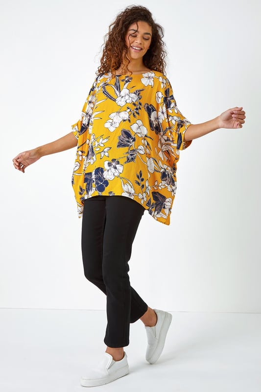 Floral Print Button Back Top from Roman. Add a light layer to your spring summer wardrobe with this short sleeve relaxed fit tee. Cut from a soft on the skin fabric, this boxy fit top is perfect for throwing on over your casual looks this season. Our large floral print top is finished with fabric covered buttons all down the back for added interest. Opt for white cropped trousers and sandals for your holiday ready ensembles.