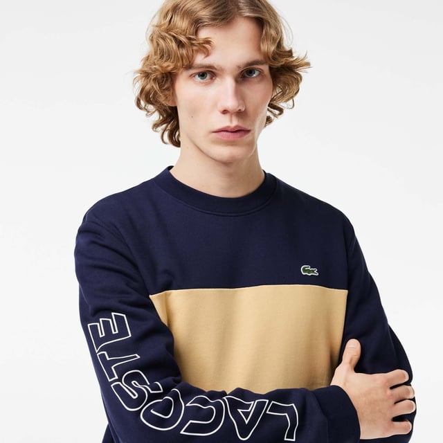 Color combination and graphics for a Lacoste dynamic and creative identity. Classic fit  natural ease on body with comfortable sleeves Our classic French terry Cut & sewn colorblock crew neck sweatshirt in mix of two different colors Rib at sleeves and bottom of body 3cm green crocodile at chest Lacoste wording 3D print at right sleeve.
