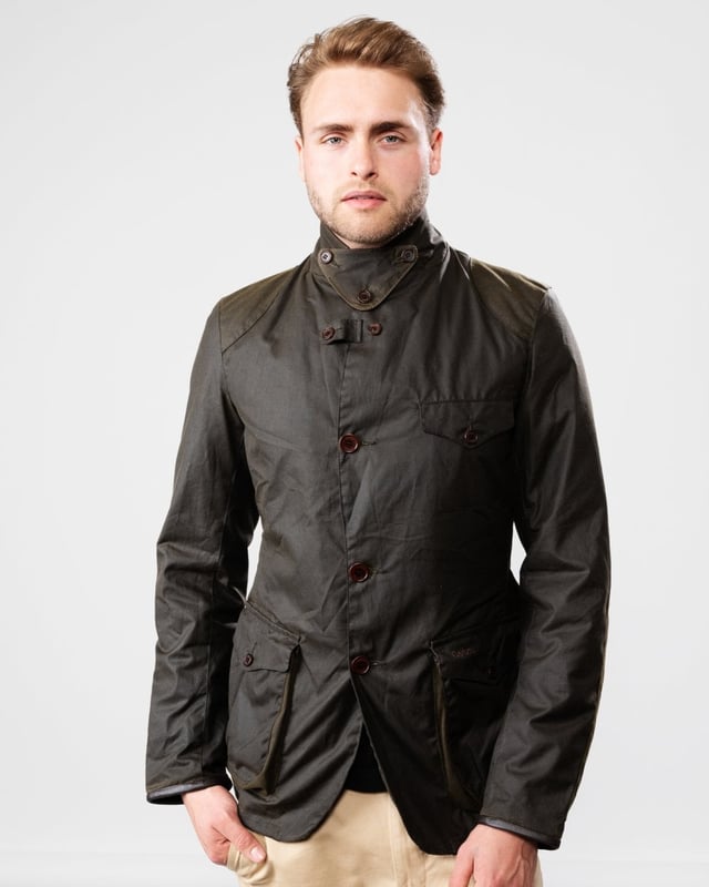 Barbour Beacon Sports Wax Jacket
As this is a slim fitting jacket, we would advise purchasing the next size up than you would normally choose. The three-pocket waxed Beacon Sports jacket is an iconic blazer-style button through, inspired by the sought-after, limited edition To Ki To Sports Jacket. Effortlessly stylish and easy to wear, the Beacon Sports Jacket is a mediumweight waxed cotton jacket featuring soft leather-bound cuff edges, shoulder and elbow patches, two zipped rear pockets and a button-up throat flap. Lined with Barbour tartan, this jacket reflects traditional Barbour elements, with classic hip-height bellows pockets and a single chest pocket. This jacket is surprisingly versatile, and looks great worn as a blazer with the collar folded down and lapels open, or with the collar turned up worn over a fine-knit jumper and scarf for a contemporary country look.

Tailored Fit
Barbour tonal embroidery to left pocket
Outer: 100% cotton (waxed)
Lining: 100% cotton
Trim: 100% wool
6oz waxed cotton
Do not wash
Sponge clean only
Back length: 69cm - 81.5cm

MWX0007