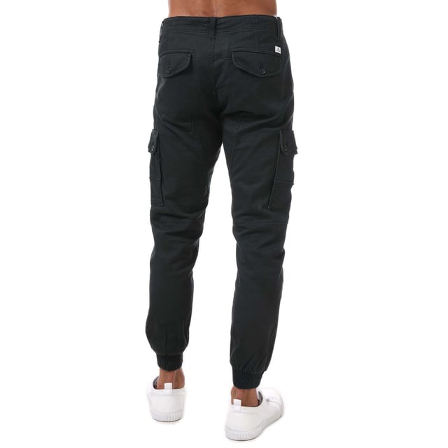 Pantalones cargo ajustados para hombre Jack Jones Paul Warner en negro. - Cierre de botón. - Bolsillos laterales. - Bolsillos con botón en la parte trasera y en las piernas. - Lavado enzimático ecológico que proporciona un aspecto desgastado. - Prenda de tejido de sarga con elasticidad. - Marca en la parte trasera. - Puños acanalados. - Ajuste entallado. - Material principal: 98% algodón 2% elastano. Lavable a máquina. - Ref: 12167596