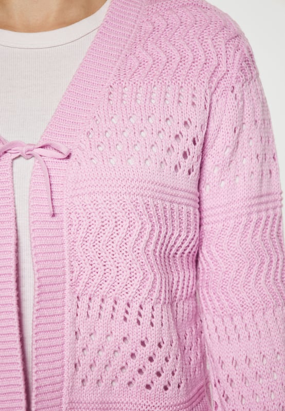 Entdecken Sie einen schicken, durchbrochenen Cardigan mit leicht verkürzter Silhouette, V-Ausschnitt mit Borten und einem Bindeverschluss vorne. Lange Ärmel mit Strickbesätzen und ein gerader Saum runden den Look ab und versprühen lässige Weiblichkeit, perfekt zum Überziehen mit jedem Outfit.  Strickjacke