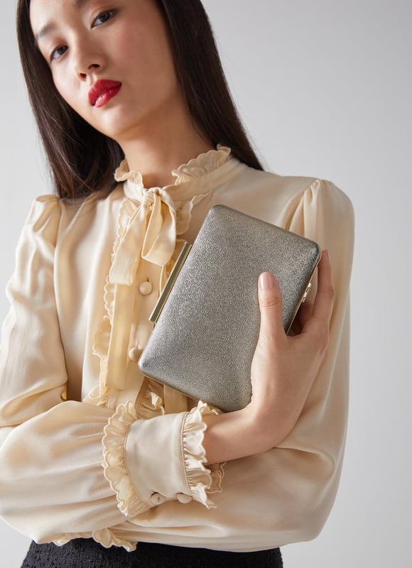 A modern interpretation of the classic box clutch, Dotty is designed for long-awaited parties. Crafted in Spain from beautiful fine glitter (which doesn't shed) in a luxurious bronze hue, it has a tapered, 3D rectangular shape, a chain shoulder strap and inside slip pocket. Wear it to add a subtle bit of shimmer and shine to any winter look.