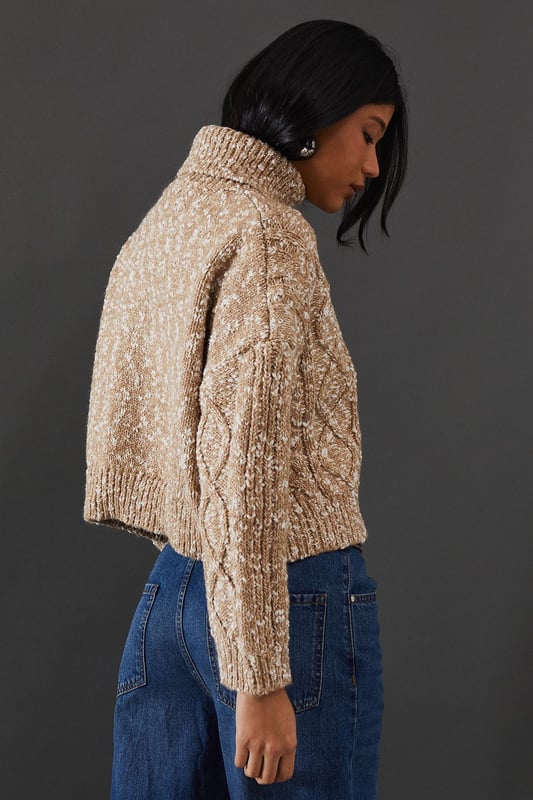Intricate cable knit pattern for a textured look
        Cosy roll neck design for extra warmth
        Relaxed, oversized fit for comfort and style
        Dropped shoulders for a contemporary silhouette
        Ribbed cuffs and hem for a snug finish
    
    This Cable Knit Roll Neck Jumper from Warehouse is the epitome of casual chic. The intricate cable knit pattern adds depth and interest to your outfit, while the oversized fit creates a relaxed, effortless vibe. Perfect for those chilly autumn days or cosy winter evenings, this jumper is versatile enough to dress up or down. For a laid-back look, pair it with wide-leg jeans and trainers, as shown in the image. To dress it up a bit, try tucking the front into a leather midi skirt and adding ankle boots. The neutral tone makes it easy to style with various colours and textures in your wardrobe. Whether you're heading to a casual family gathering or meeting friends for a coffee, this jumper will keep you warm and stylish. Its timeless design ensures it will remain a staple in your wardrobe for seasons to come.