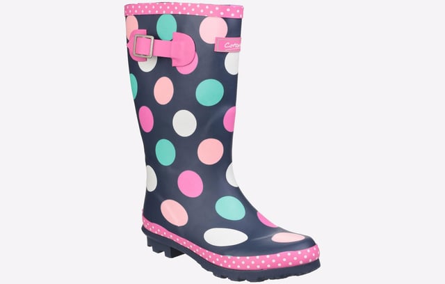 Perfect for the upcoming months, these Cotswold Dotty wellingtons are perfect for taking the rainy weather in stride and making a splash. The waterproof rubber upper is constructed in a classic wellington silhouette, with a deep navy colourway adorned with fun multi-coloured dots and a chic pink trim sure to brighten up your little ones day no matter what the weather. The slip-on design ensures easy on / off wear, with an adjustable buckle feature to the side for the perfect fit and feel. A soft textile lining and padded footbed provide comfort, with a durable rubber outsole and cleated heel for enhanced traction, making them a wardrobe essential for the upcoming months. 
 - Waterproof rubber outsole
 - Adjustable buckle feature
 - Textile lined with removable insole
 - Cushioned footbed
 - Slip on design
 - Rubber traction sole unit with chunky cleated heel
 - Cotswold branding
 *Do your bit for the environment as every pair of these Cotswold Shoes sold supports National Forest tree planting.*
 Please note: These boots come in a branded Cotswold bag and are not boxed.