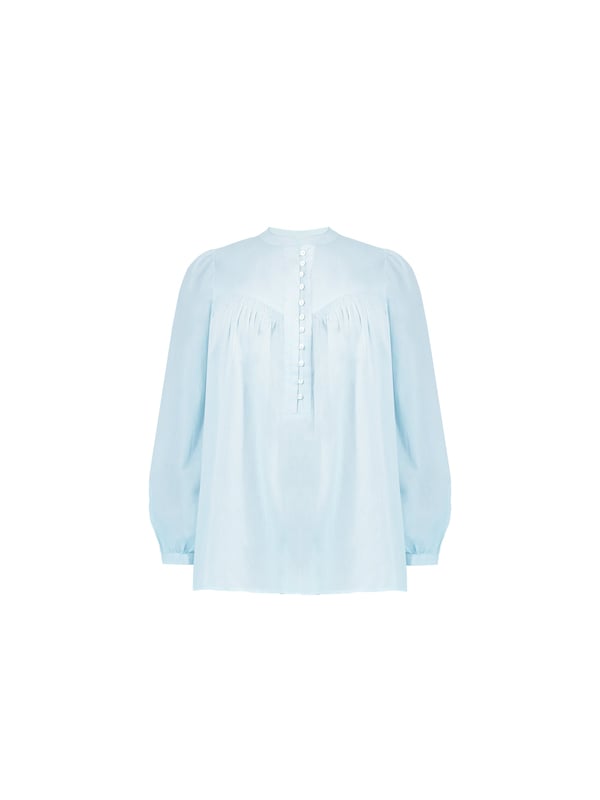 In classic blue, this blouse is cut from the softest of cottons. With a nehru collar, it has a button-up front placket with pretty rouleau buttons, as well as shirring detail at the yoke. Full-length sleeves with button up cuffs create an elegant silhouette, especially when combined with its high-low hem which provides that all-important coverage.