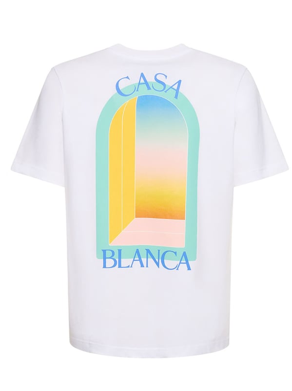 The T-shirt features a classic cut with a round neckline, offering a timeless silhouette. The front is graced with a vibrant, stylised print depicting an abstract representation of a window or gateway, bathed in the soft pastel hues of blue, yellow, and orange, evoking the serene beauty of a sunset. 