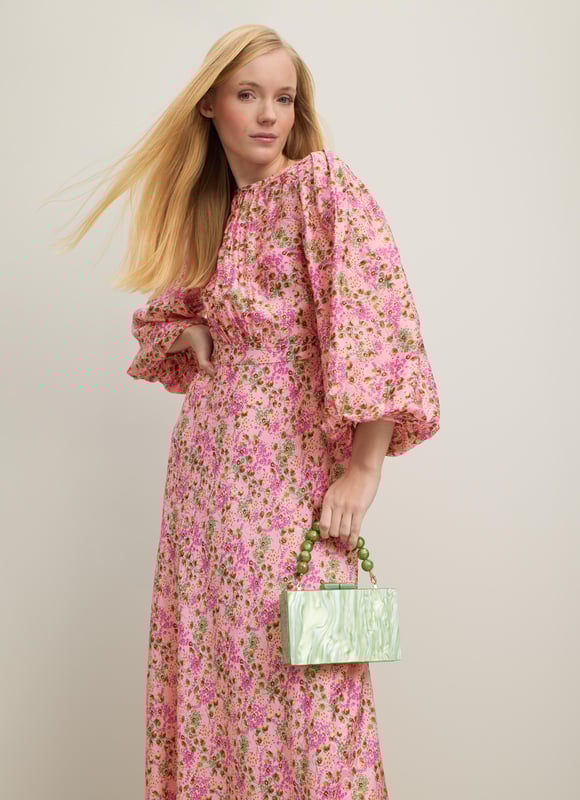 A beautiful new dress in our Royal Ascot collection, the Lois is pretty in pink with a reimagition of a French mid 19th century print. Crafted from a slinky viscose-silk blend in pink with a squiggle jacquard and a neon garden print, it has a round neck with pleating detail, puff shoulders, voluminous balloon sleeves and a long, floaty cut falling to a midi length. Wear it with heels and a hat to cheer on the winners.