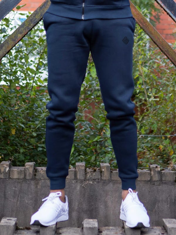 Enzo Mens Pullover Hoodie Tracksuit Set. Enzo Embroidery Logo on Chest. Hoodie with Drawstring. Ribbed Waist and Cuffs. Kangaroo Pockets. Enzo Mens Casual Designer Tracksuit Joggers. Adjustable Waist with Drawstring. 2 Pocket Design. Colours Available: Black, Grey, Khaki, Navy