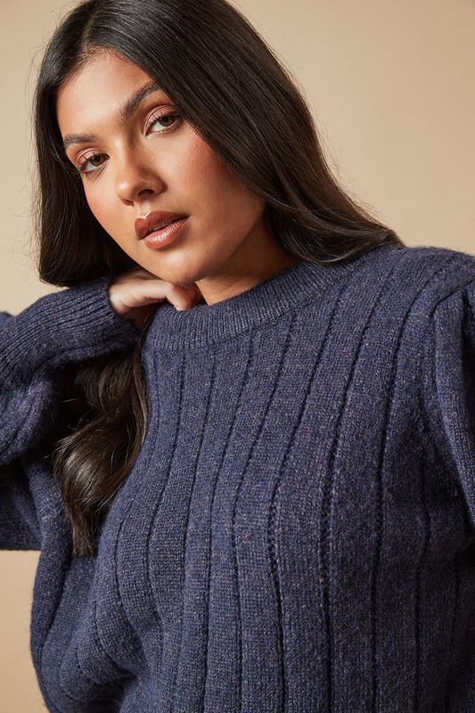 Ribbed knit texture for added visual interest
        Elegant bow detail at the back for a feminine touch
        Voluminous balloon sleeves create a striking silhouette
        Crew neckline for a classic finish
        Versatile design suitable for various casual occasions
    
    This Oasis Bow Back Ribbed Jumper effortlessly combines comfort with style, making it a must-have addition to your wardrobe. The ribbed knit texture adds depth and interest to the design, while the charming bow detail at the back introduces a delightful feminine flair. The jumper's standout feature is undoubtedly its voluminous balloon sleeves, which create a dramatic and eye-catching silhouette. For a casual yet chic ensemble, pair this jumper with a pleated leather-look skirt and knee-high boots, as shown in the image. This versatile piece is perfect for family gatherings, brunch dates, or casual outings with friends. To dress it up for evening drinks, consider swapping the boots for heeled ankle booties and adding statement earrings. The jumper's adaptable nature ensures it will become a go-to item in your wardrobe, easily transitioning from day to night with simple styling tweaks.