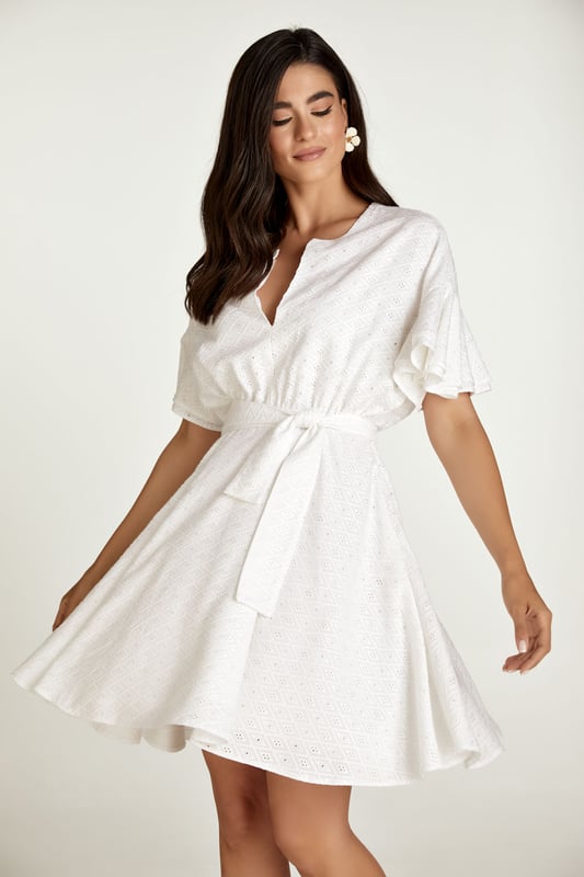 Este vestido blanco está confeccionado en tejido de viscosa bordado tono sobre tono. Tiene mangas cortas con doble volante y hombros caídos. Tiene escote redondo con abertura en V en la parte delantera. Debajo del busto hay una costura curva bajo la cual el vestido se abre en forma de campana. Hay una cremallera oculta en el interior que permite ponerse el vestido fácilmente. Está forrado. El vestido se puede llevar con o sin cinturón que está confeccionado en el mismo tejido. El cinturón está incluido.