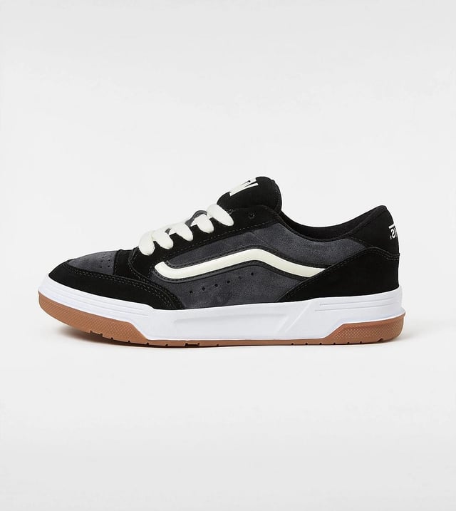 Vans Hylane Schwarze Turnschuhe Tauchen Sie mit Sneakers im Retro-Stil ein, die über Wildleder- und Synthetik-Obermaterialien für Strapazierfähigkeit und Komfort verfügen. Gestaltet mit einer 3D-gelackten Seitenstreife und bestickten Logos für einen kühnen, auffälligen Look. Die klobige Silhouette und die gepolsterte Skater-Zunge vermitteln eine nostalgische Atmosphäre, während die klassische Gummiprofilsohle für zuverlässigen Halt und Traktion sorgt.