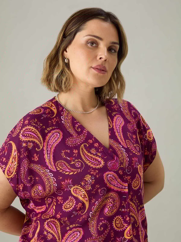 In a pretty purple-red paisley print, this pleat front top is cut from a lightweight woven fabric thats so comfortable to wear. With a lengthening V-neck, this top has short sleeves and pleat detailing through the centre front which complements its loose, A-line body. Pair this with jeans or leggings for the perfect laid-back look.
